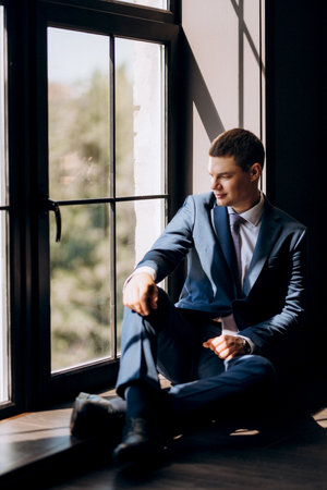 portrait of groom in blue three piece suit with tie on wedding day in hotelの写真素材