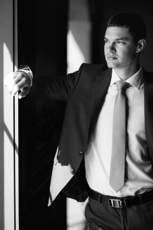 portrait of groom in blue three piece suit with tie on wedding day in hotelの写真素材