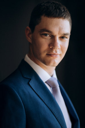 portrait of groom in blue three piece suit with tie on wedding day in hotelの写真素材
