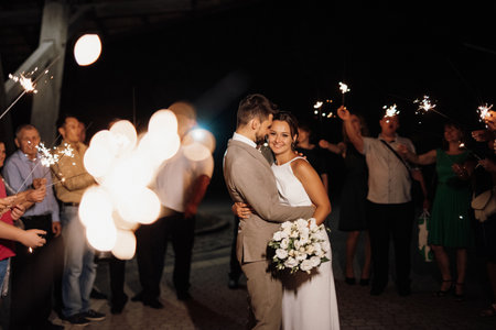 newlyweds at a wedding in the corridor of sparklersの写真素材