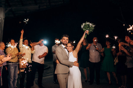 newlyweds at a wedding in the corridor of sparklersの写真素材