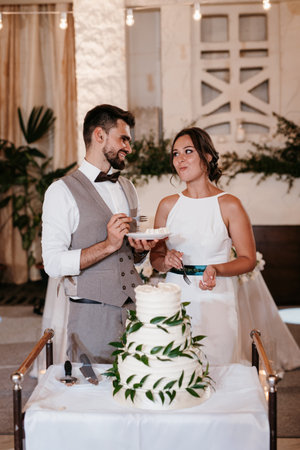 newlyweds happily cut, laugh and taste the wedding cakeの写真素材