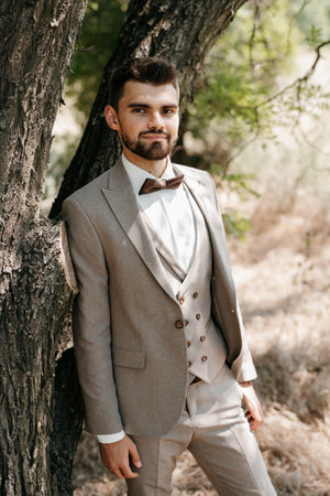 portrait of a guy in a gray three-piece suit near a treeの写真素材