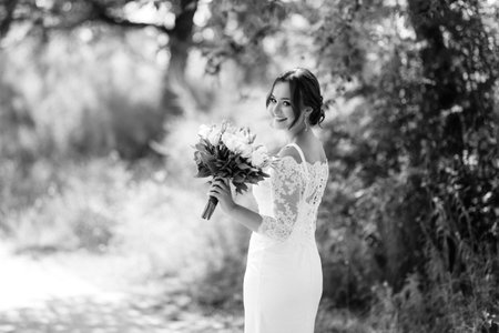 young girl in a beautiful dress with a bouquet on a path in a summer parkの写真素材