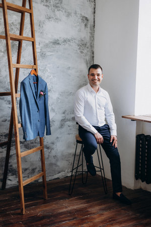 portrait of a young groom in a blue jacket and white shirt in a bright studio on a wedding dayの写真素材
