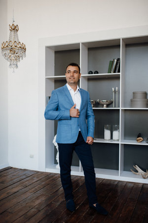 portrait of a young groom in a blue jacket and white shirt in a bright studio on a wedding dayの写真素材