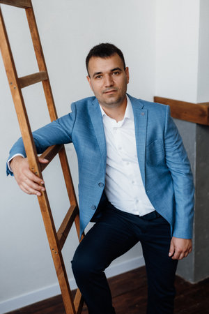 portrait of a young groom in a blue jacket and white shirt in a bright studio on a wedding dayの写真素材