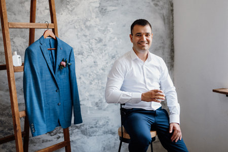 portrait of a young groom in a blue jacket and white shirt in a bright studio on a wedding dayの写真素材