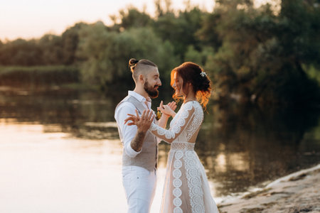 bride girl and groom near the river at sunset lightの写真素材