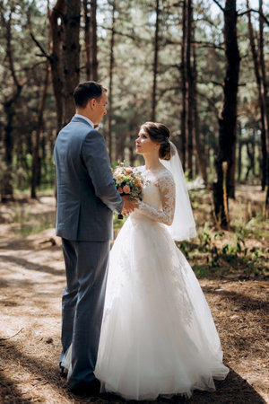 portrait of an elegant groom in a blue suit in a deciduous forest with a bouquetの写真素材