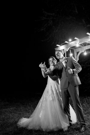 bride and groom against the backdrop of an evening wedding arch with warm live fireの写真素材