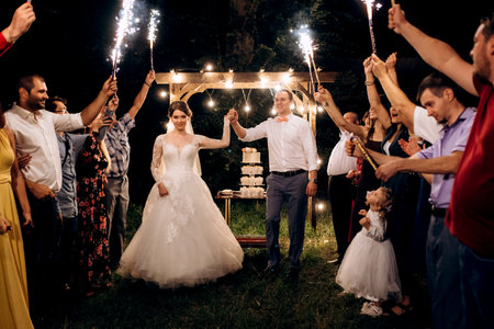 cold fire from cake candles and fireworks in the hands of people around the newlywedsの写真素材