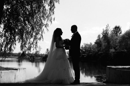 A bride in a white dress and a groom in a blue suit with a bow tie on a walk in the park on their wedding dayの写真素材