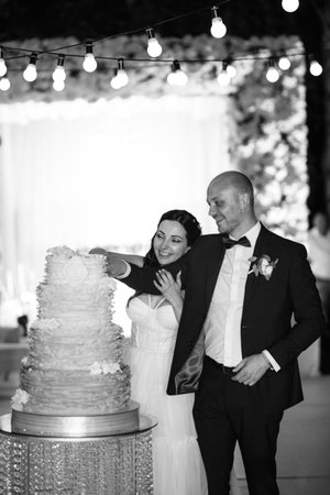 newlyweds happily cut, laugh and taste the wedding cakeの写真素材