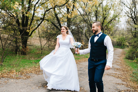 bride and groom walking along a path in an autumn forest