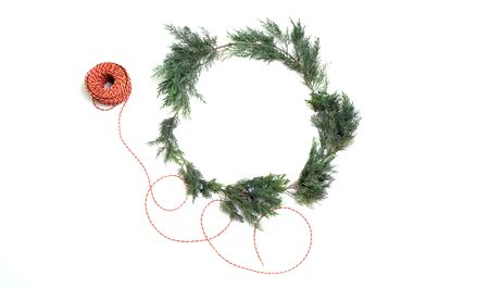 Christmas wreath of juniper with coil of red thread white background top viewの写真素材