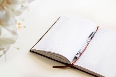 Open journal, a bouquet of lilies on a white backgroundの写真素材