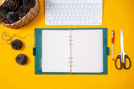 open notebook journal with Christmas cones in a wicker basket yellow backgroundの写真素材