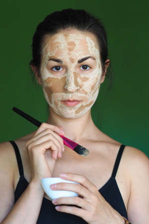 young brunette woman with a clay homemade mask on her faceの写真素材