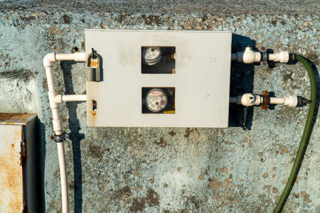 Close-up of a white electric meter on a concrete wall.