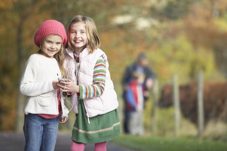 Two Young Girl Listening To MP3 Player Outdoorsの写真素材