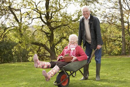 Senior Couple Man Giving Woman Ride In Wheelbarrowの写真素材