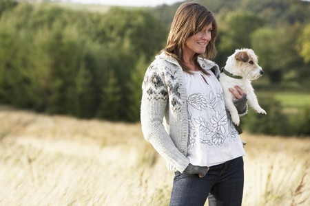 Young Woman Outdoors In Autumn Landscape Holding Dogの写真素材