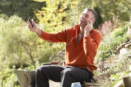 Man Outdoors Listening To MP3 Player Whilst On Break From Gardeningの写真素材