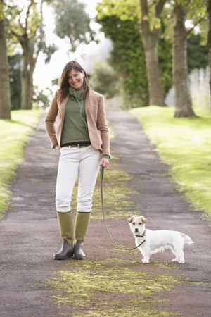 Woman Taking Dog For Walk Outdoors In Autumn Parkの写真素材