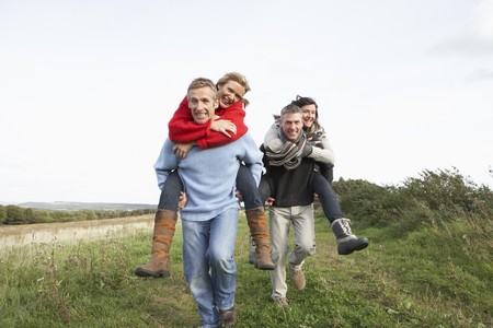 Two Couples Having Piggyback Ride In Autumn Landscapeの写真素材