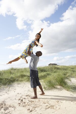 Energetic Young Couple Having Fun In Dunes By Beachの写真素材