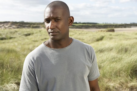 Thoughtful Young Man Standing On Beach Amongst Dunesの写真素材