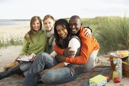 Group Of Young Friends Enjoying Picnic On Beach Togetherの写真素材
