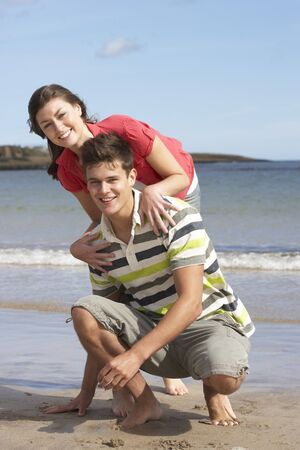 Affectionate Teenage Couple Having Fun On Beachの写真素材