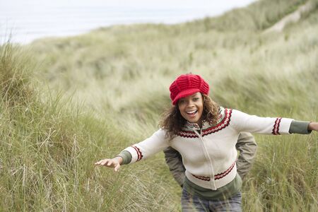 Teenage Girl Walking Through Sand Dunes Wearing Warm Clothingの写真素材