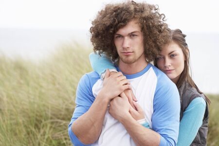 Young Couple Walking Through Sand Dunes Wearing Warm Clothingの写真素材