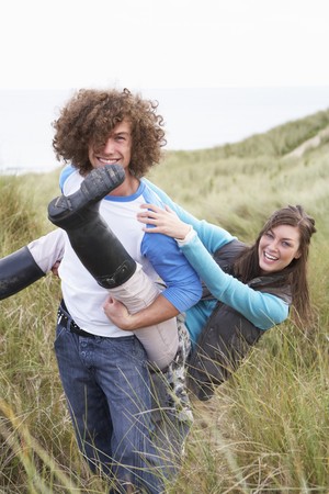 Teenage Couple Having Piggy Back Ride In Sand Dunesの写真素材