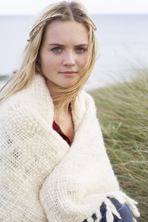 Young Woman Standing In Sand Dunes Wrapped In Blanketの写真素材