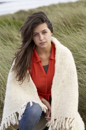 Young Woman Standing In Sand Dunes Wrapped In Blanketの写真素材