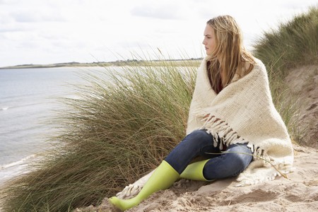 Young Woman Standing In Sand Dunes Wrapped In Blanketの写真素材