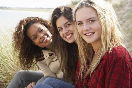 Three Teenage Girls Sitting In Sand Dunes Togetherの写真素材