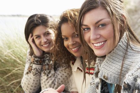Three Young Girls Sitting In Sand Dunes Togetherの写真素材