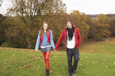 Romantic Teenage Couple Walking Through Autumn Landscapeの写真素材