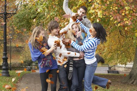 Group Of Teenage Friends Throwing Leaves In Autumn Landscapeの写真素材