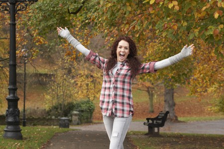 Teenage Girl Standing In Autumn Park With Arms Outstretchedの写真素材