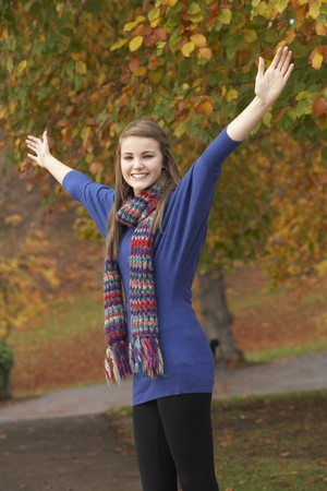 Teenage Girl Standing In Autumn Park With Arms Outstretchedの写真素材