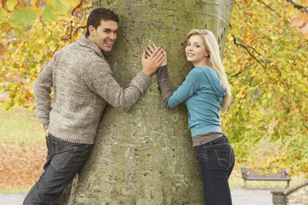 Romantic Teenage Couple By Tree In Autumn Parkの写真素材