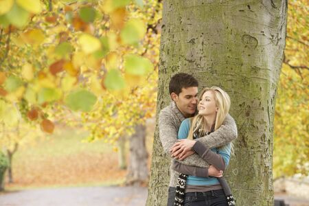 Romantic Teenage Couple By Tree In Autumn Parkの写真素材