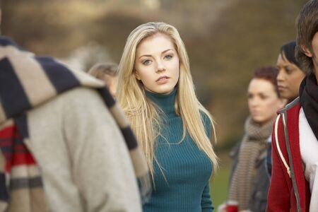 Teenage Girl Surrounded By Friends In Outdoor Autumn Landscapeの写真素材