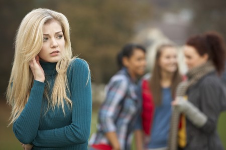 Upset Teenage Girl With Friends Gossiping In Backgroundの写真素材